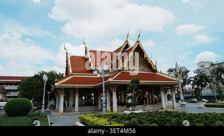 Breite Front Mit Vollem Blick Auf Traditionelle Thailändische Tempelhalle, Rotes Fliesendach, Goldenes Vergoldetes Ornament Stockfoto