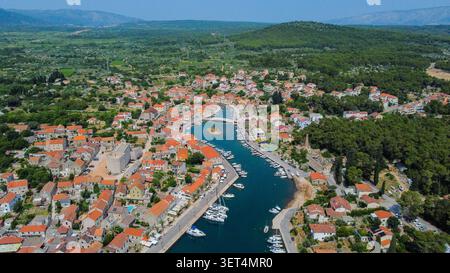 Luftaufnahme mit der Küstenstadt vrboska auf der Insel hvar. Boote, die im Kanal geparkt sind, umgeben von historischen Gebäuden mit roten Dächern Stockfoto