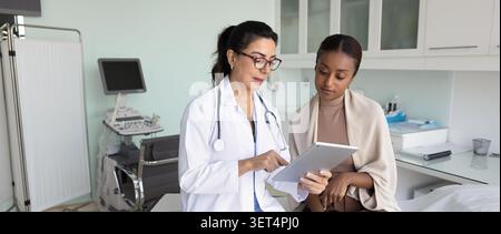 Ernsthafte erfahrene reife Ärztin, die den Patienten konsultiert Stockfoto