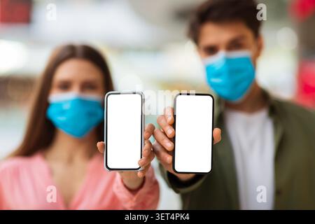 Ein Paar, Das Smartphones Mit Leeren Bildschirmen Hält, Masken Trägt, Inneneinrichtung, Nicht Erkennbar Stockfoto