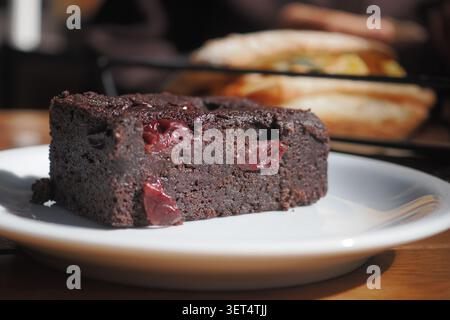 Brownie mit Kirschen auf einem weißen Teller in einem Café Stockfoto