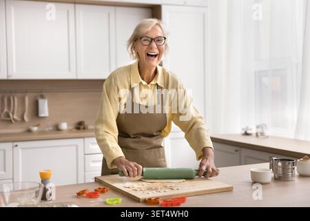 Glückliche Frau, die allein in der modernen Küche Nachtisch zubereitet Stockfoto