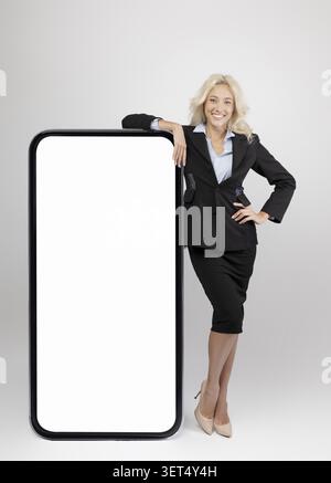 Selbstbewusste Geschäftsfrau Lächelt Und Präsentiert Leere Smartphone-Mockup, Büroumgebung, Professionelles Konzept Stockfoto