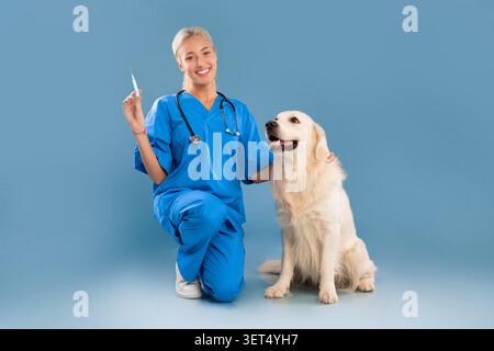 Lächelnde Kaukasische Tierärztin Hält Spritze Neben Golden Retriever, Clinic Setting, Healthcare Concept Stockfoto