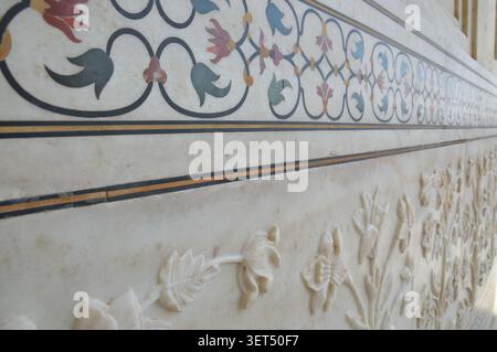 Nahaufnahme der zarten floralen Pietra dura-Inlayarbeiten und der Flachrelief-Marmorschnitzereien an der Außenwand des Taj Mahal. Stockfoto