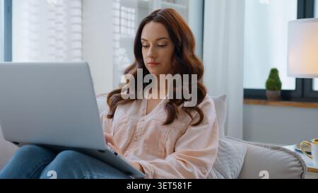 Konzentrierte kaukasische Frau mit Laptop entspannen Sie sich zu Hause auf der Couch weibliches Mädchen, das Computer Internet-Technologie im Cyberspace surft und sich auf Sofa-Dame entspannt Stockfoto
