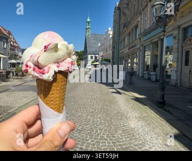 Ein Eis in einem Kegel halten und essen, während Sie in einer Stadt sind. Stockfoto