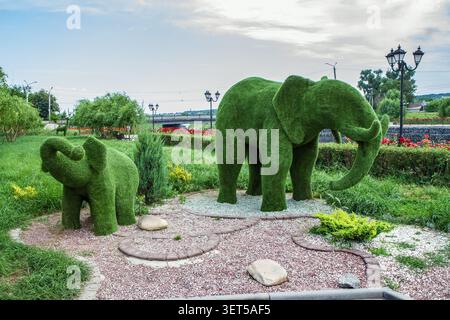 Die Gestalten des Topiars in Form eines Elefanten und eines Babyelefanten. Künstliche Büsche in der Landschaftsgestaltung des Stadtparks. Stockfoto