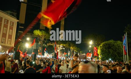 Tirana, Albanien – 20. Juni 2026: Eine große albanische Flagge weht über Demonstranten, die sich nachts in Zentral-Tirana versammelten. Stockfoto