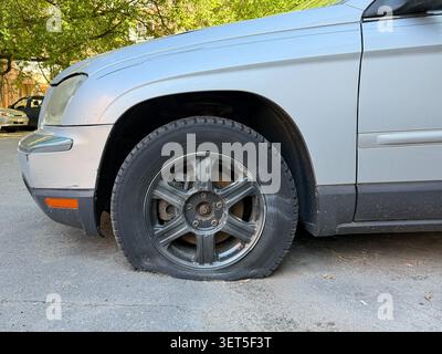 Platter Reifen auf geparkten silbernen Pkw-Ständen auf Stadtstraßen, Probleme mit der Fahrzeugwartung, Transportstörungen, Sicherheit am Straßenrand. Kfz-Service Stockfoto