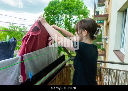 Seitenansicht einer Frau, die Nasswäsche auf der Trocknungslinie im Freien organisiert Stockfoto