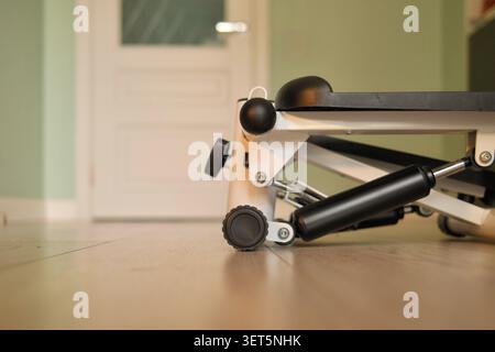 Kompakter Mini-Stepper-Übungsgerät auf Holzboden zu Hause. Konzept der Home Fitness, gesunde Lebensweise, Cardio-Workouts, Gewichtsverlust Stockfoto