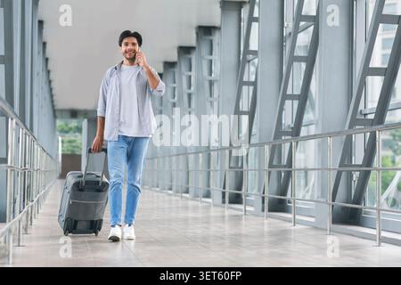 Jungen Touristen am Telefon sprechen, Wandern im Gepäck am Flughafen Stockfoto