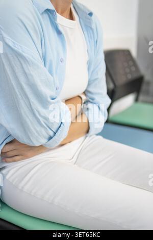 Person, die an starken Bauchschmerzen, Verdauungsstörungen oder Menstruationskrämpfen leidet, sich unwohl fühlt und ein Gesundheitsproblem erlebt, hält ihre Sto Stockfoto