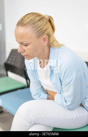 Frau, die sich unwohl fühlt und unter starken Bauchschmerzen oder starken Bauchkrämpfen leidet, die möglicherweise mit der Menstruation zusammenhängen und ihren leidenden Bauch berührt Stockfoto