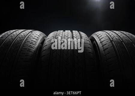 Autoreifen auf dunklem Hintergrund. Nahaufnahme der neuen Sommerreifen mit dramatischem Licht. Vorderansicht. Stockfoto