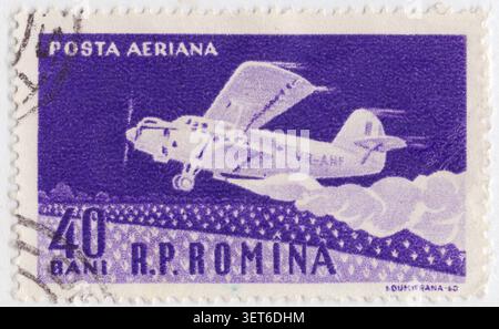 RUMÄNIEN - 15. Juni 1960: 40 Verbot violetter Luftpoststempel AN-2 landwirtschaftliche Doppeldecker Spritzpflanzen. 50 Jahre Erstflug der rumänischen Flugzeuge von Aurel Vlaic. Der Antonov-Doppeldecker ist dargestellt, der landwirtschaftliche Flugaufgaben durchführt, einschließlich des Sprühens von Feldern über einem offenen Feld. Das Flugzeug hat die rumänische Zivilregistrierung YR-ANF und gehört zum Versorgungsluftfahrtsektor, der Mitte des 20. Jahrhunderts staatliche Agrarinitiativen unterstützte. Dieser robuste, sowjetisch konstruierte Doppeldecker wurde aufgrund seiner kurzen Startfähigkeit und Zuverlässigkeit in ganz Osteuropa weit verbreitet Stockfoto