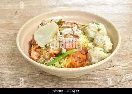 Chinesische Eigelnudeln mit rotem Barbecue-Schweinefleisch und Knödeln mit Krabbenfleisch in klarer Suppe auf einer Schüssel Stockfoto