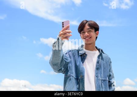 Horizontales, flaches Lifestyle-Foto eines hübschen jungen südostasiatischen Thai-Isan-Mannes, der glücklich lächelt und dabei in die Kamera schaut Stockfoto