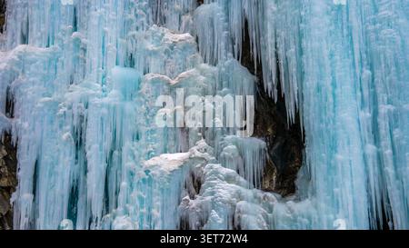 Aus der Vogelperspektive sehen Sie einen riesigen gefrorenen Wasserfall mit komplexen blauen Eiszapfen, die von einer zerklüfteten Felswände im Khunjerab-Nationalpark in Gilgit, Pakistan hängen. Stockfoto
