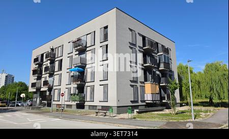 Weitwinkelblick auf ein modernes kubisches mehrstöckiges Wohngebäude mit vertikalen Fenstern und individuellen Balkonen mit Metallgeländern Stockfoto