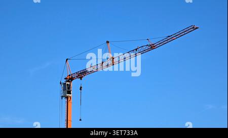 Ein flacher, klarer Schuss eines massiven Stahlgitterkrans mit Fahrerkabine, Gegengewichten und Seilrollen aus Stahl unter hellem, sonnigem Himmel Stockfoto