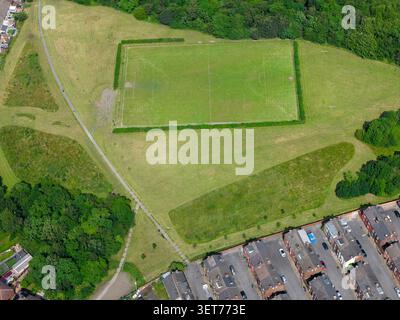 Drohnenblick auf einen Fußballplatz und öffentliche Grünflächen in Leeds, umgeben von Waldwegen und Terrassenhäusern, die die Gemeinde spor zeigen Stockfoto