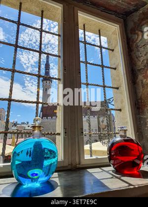 Tallinn, Estland - 3. Juli 2020: Blick durch einen alten schmiedeeisernen Fenstergrill auf die historische Rathausapotheke (Raeapteek) mit zwei Glaspotio Stockfoto