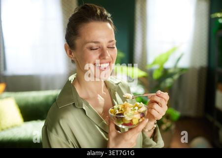 Mit geschlossenen Augen genießt eine Frau einen Löffel frischer Obstsalat, was einen gesunden Lebensstil und die einfache Freude an nahrhaftem Snack widerspiegelt Stockfoto