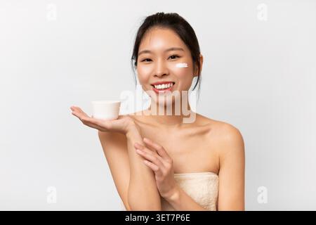 Lächelnde Asiatische Frau, Die Hautpflege-Creme Zu Hause Anwendet, Wellness-Konzept Stockfoto