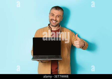 Lächelnder Kaukasier Mit Laptop Und Daumen Hoch, Büroeinrichtung, Geschäftskonzept Stockfoto
