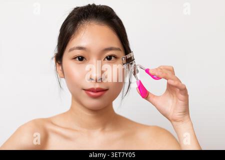 Junge Asiatische Frau, Die Wimpernlocken Für Make-Up Zu Hause Verwendet, Hautpflege Routine Stockfoto