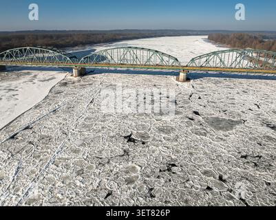 Metallbrücke über gefrorenen Fluss mit Schollen. Luftaufnahme über den Winter in Polen. Stockfoto