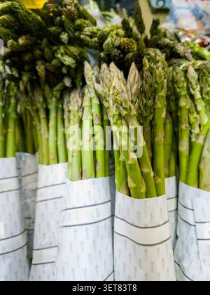 Eine Nahaufnahme mehrerer Bündel frischer Spargel, die ordentlich für den Verkauf auf einem Erzeugnismarkt gestapelt sind. Stockfoto