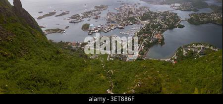 Panoramablick auf den Lofoten-Archipel mit Küstenstadt mit Hafen, Fischerbooten, umliegenden Inseln, Fjorden und dramatischen Stockfoto