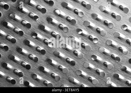 Die Oberfläche aus Metall mit kreisförmigen Löchern und gebürsteter Textur, abstraktes industrielles Hintergrundmuster, das Design bietet eine moderne und geometrische Ästhetik Stockfoto