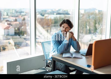 Durchdachter Kaukasischer Mann, Der Am Schreibtisch Mit Laptop Arbeitet, Business-Konzept Stockfoto