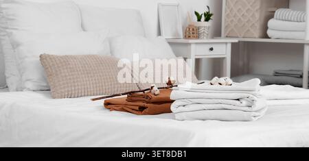 Frisch gewaschene weiße und braune Baumwollbettwäsche mit dekorativen Kissen und Baumwollballen auf einem sauberen Bett, diese Einrichtung hebt hochwertige Textilien und einen hervor Stockfoto