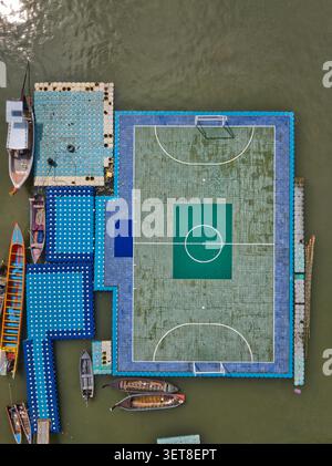 Blick aus der Vogelperspektive auf das schwimmende Fußballfeld von Koh Panyi, umgeben von traditionellen Langboot-Booten, die auf dem Wasser in Ko Panyi, Phang Nga, Thailand, verankert sind. Stockfoto