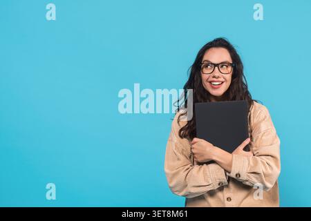 Happy Young Latina Woman Hält Laptop Und Lächelnd, Blauer Hintergrund Stockfoto