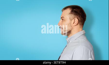 Man Profile Porträt, Fokussierter Ausdruck, Seitenansicht, Blauer Hintergrund, Geschäftskonzept Stockfoto