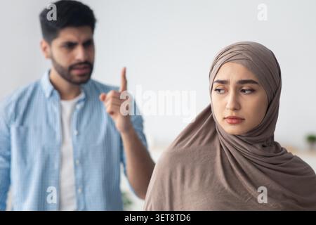 Besorgte Junge Frau In Hijab Mit Aufgebrachtem Jungen Mann, Konflikten, Emotionalen Gesprächen Stockfoto