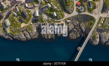 Atemberaubende Luftperspektive auf die Lofoten-Inseln mit traditionellen norwegischen Küstenhäusern auf dramatischen felsigen Klippen mit Blick auf die Küste Stockfoto