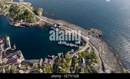 Panoramablick auf ein malerisches Fischerdorf der Lofoten, eingebettet zwischen felsigen Klippen und türkisfarbenem Wasser, mit traditionellem Rot Stockfoto