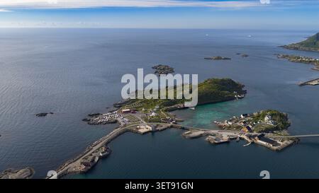 Atemberaubendes Panorama der Lofoten-Inseln mit traditionellem Fischerdorf mit roten Booten, grünen Bergen, türkisfarbenem Wasser und felsigem Gestein Stockfoto