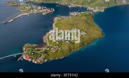 Panoramablick auf die Lofoten Inseln mit Dörfern an der Küste, eingebettet zwischen dramatischen grünen Bergen und tiefblauem Fjord Stockfoto