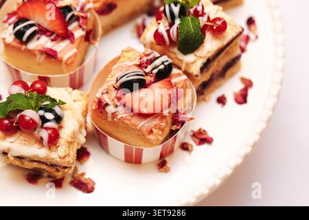 Mini-Käsekuchen-Desserts mit frischen Erdbeeren und Beeren. Süßer Backwarenhintergrund für Feiern, Desserttische und Kaffeepausen. Stockfoto