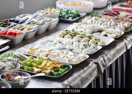 Buffettisch mit Käsesorten, Hüttenkäse, Trauben und Vorspeisen. Catering-Speisen im Hintergrund für Feiern, Empfänge und Geschäftsveranstaltungen. Stockfoto