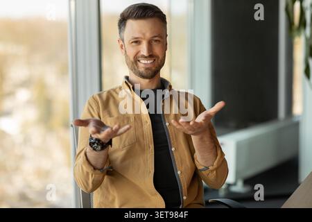 Lächelnder Kaukasier, Der Mit Offenen Händen Im Modernen Büro, Geschäftskonzept Stockfoto