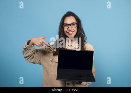Lächelnde Junge Hispanische Frau, Die Auf Laptop Mit Leerem Bildschirm Zeigt, Geschäftskonzept Stockfoto